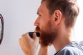 Man cutting his own beard and mustache with scissors and comb. Caucasian red bearded male trimming hair on face at home Royalty Free Stock Photo