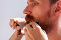 Man cutting his own beard and mustache with scissors and comb. Caucasian red bearded male trimming hair on face at home Royalty Free Stock Photo