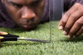 Man Cutting The Measured Grass With Scissor