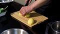 A man cutting a peeled potato on a wooden board. Art. Close up of male chef preparing a dish and using a steel knife for Royalty Free Stock Photo