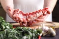 Man cutting rack of lamb on wooden board at restaurant kitchen. Chef preparing fresh meat for cooking Royalty Free Stock Photo