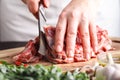 Man cutting rack of lamb on wooden board at restaurant kitchen. Chef preparing fresh meat for cooking Royalty Free Stock Photo