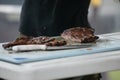 A man cutting up barbeque ribs from the smoker grill on cutting board with gloves on and a large knife. Royalty Free Stock Photo