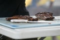 A man cutting up barbeque ribs from the smoker grill on cutting board with gloves on and a large knife. Royalty Free Stock Photo