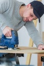 Man cutting woodplank using bandsaw