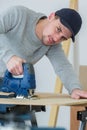 man cutting woodplank using bandsaw