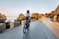 Man cyclist pedaling on a road bike outdoors in sun set