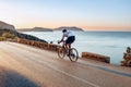 Man cyclist pedaling on a road bike outdoors in sun set