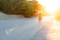 Man cyclist pedaling on a road bike outdoors in sun set