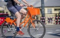 Man cyclist rides socially rented orange bicycle at crossroad on city street