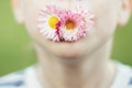 Man with a daisy flower on a green background close. child mouth with flower