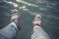 Man dangling feet over water