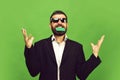 Man with dark beard holds green business card in teeth