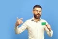 Man with dark beard in white shirt holds business card