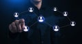 A man in dark clothing interacts with a digital interface featuring interconnected human icon nodes on a world map background