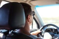 A man with dark glasses is driving a car. Road safety, traffic rules, auto travel, navigator