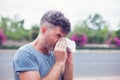 Man sneezing in a tissue outdoor. Pollen allergy, Springtime. Royalty Free Stock Photo