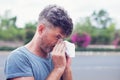 Man sneezing in a tissue outdoors. Pollen allergy, Springtime. Royalty Free Stock Photo