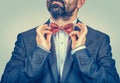 Man in dark suit,  blue shirt, adjusting red butterfly bow, tie Royalty Free Stock Photo