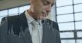 Man in dark suit, light tie analyzing bar and line graph overlay by mullioned windows Royalty Free Stock Photo