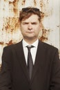 Man in dark suit  and tie posing for portrait by rusty white wall Royalty Free Stock Photo