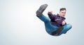 Man in dark violet hooded sweatshirt and jeans in karate fight jump, on light blue background Royalty Free Stock Photo