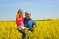 Man with daughter on hand standing in flowering rapeseed field Royalty Free Stock Photo