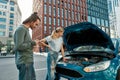 Man decided to help girl with her auto, he is trying to call emergency car service while they both standing near her Royalty Free Stock Photo