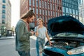 Man decided to help girl with her auto, he is trying to call emergency car service while they both standing near her Royalty Free Stock Photo