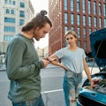 Man decided to help girl with her auto, he is trying to call emergency car service while they both standing near her Royalty Free Stock Photo