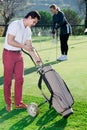 Man deciding on club while girl hitting ball Royalty Free Stock Photo