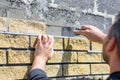 Man decorates the facade of the fence with decorative torn bricks, close up. Work at home during quarantine. Do it yourself