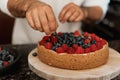 Man decorating a homemade cheesecake with fresh berries. Cooking process Royalty Free Stock Photo