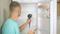 A man defrost the refrigerator with a hairdryer. adventures of strange people