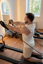 Kneeling pulley exercise, practicing on reformer pulley row focusing on shoulder control Royalty Free Stock Photo