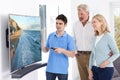 Man Demonstrating New Television To Mature Couple At Home Royalty Free Stock Photo