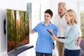 Man Demonstrating New Television To Mature Couple At Home Royalty Free Stock Photo