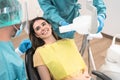 Man dentist operating young smiling woman in dental clinic