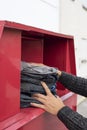 Man depositing used clothes in a clothing bin