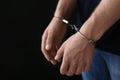 Man detained in handcuffs dark background, space for text. Criminal law