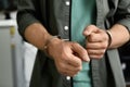 Man detained in handcuffs indoors, closeup . Criminal law Royalty Free Stock Photo