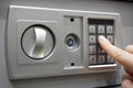 The man dials the code to close the safe. Grey safe closure, numeric keypad. A man presses the keys on the digital panel on the