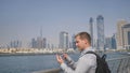 The man dials the number on the phone and talks on the background of the panorama of Dubai. Hand close-up.