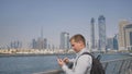 The man dials the number on the phone and talks on the background of the panorama of Dubai. Hand close-up.