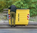 Man digging through garbage in yellow recycling container
