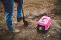 Man digging a grave in pet cemetery. Gravedigger digs pet burial hole in wooded area. Carrying box for animals with toy on