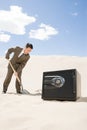 Man digging by safe in desert Royalty Free Stock Photo