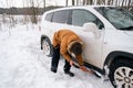 A man digs out a stalled car in the snow with a car shovel. Transport in winter got stuck in a snowdrift after a snowfall, sat on Royalty Free Stock Photo