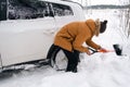 A man digs out a stalled car in the snow with a car shovel. Transport in winter got stuck in a snowdrift after a snowfall, sat on Royalty Free Stock Photo