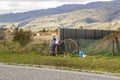 Man diligently welds metal construction in an outdoor setting. Surrounded by fields, mountains, and a sky adorned with